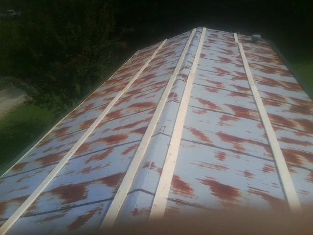 Rusted metal roof panels with new wood purlins before replacement — Storm Damage Roof Repair in Grand Meadow by Roofing Brothers