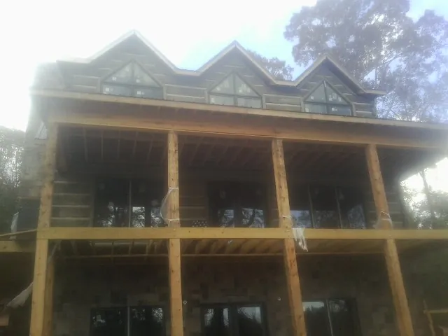 Dormers and porch framing on a large log home under construction — Roof Coating work by our crew in Grand Meadow