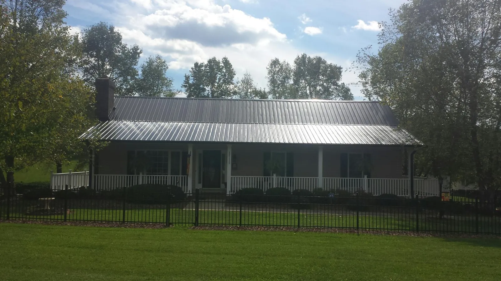 Gray metal roof on a brick ranch with a full width front porch — Gutter Guard Installation work by our crew in Grand Meadow