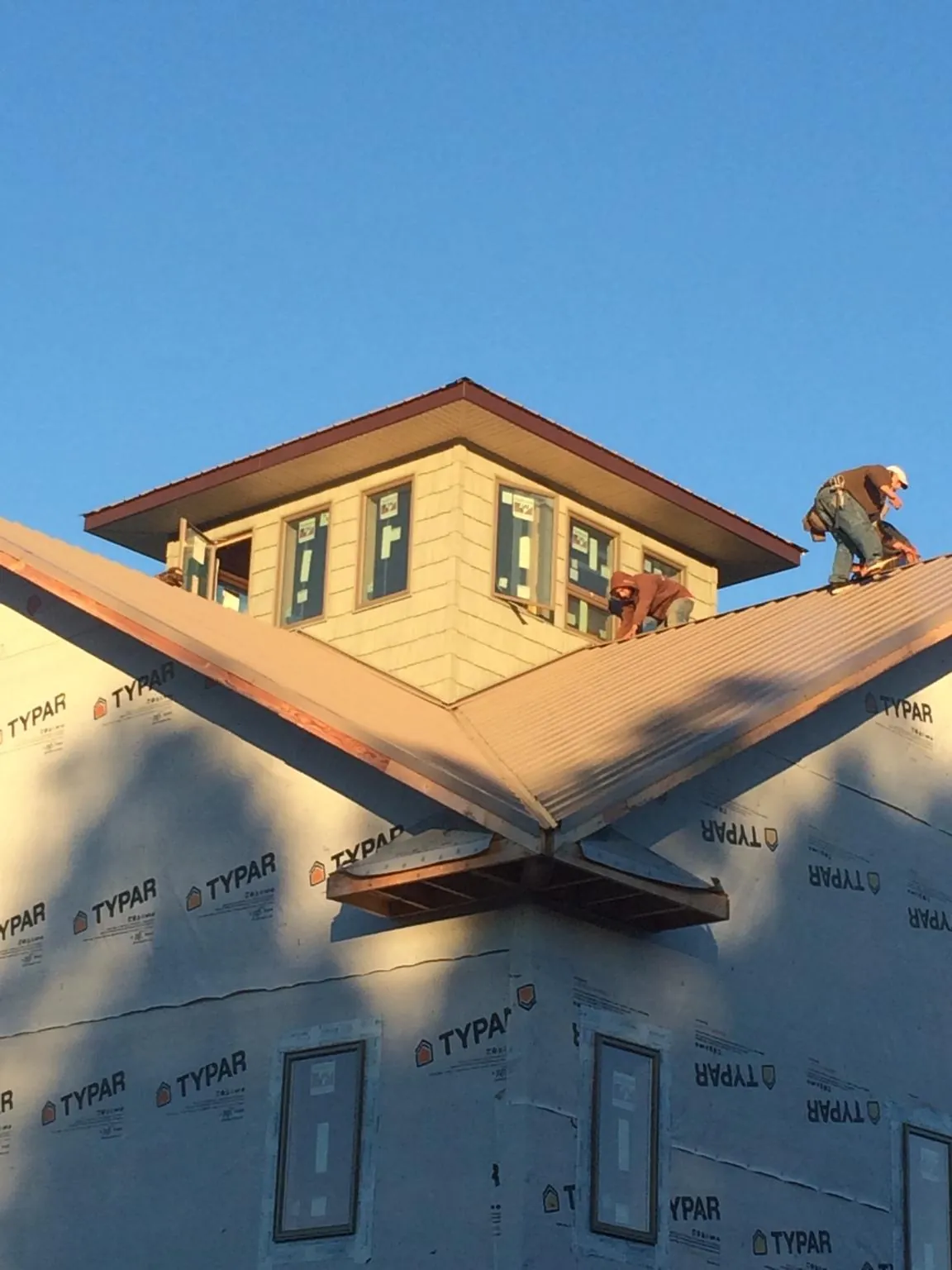 Roofers working around a rooftop cupola on a new metal roof at sunset — Roof Waterproofing in Grand Meadow by Roofing Brothers